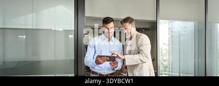 Team of two happy business men working standing in office using digital tablet. Stock Photo