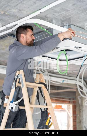 Hvac technician installing air conditioning unit in construction site Stock Photo