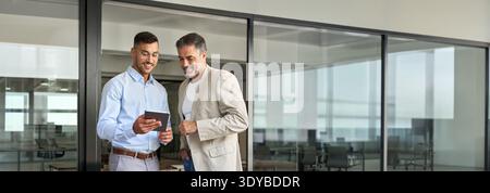 Team of two happy business men working standing in office using digital tablet. Stock Photo