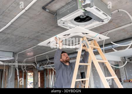 Technician installing rooftop air conditioning unit on construction ceiling Stock Photo