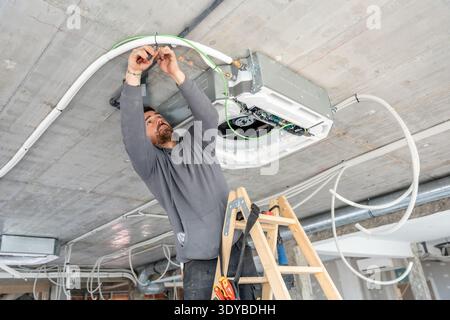 Hvac technician installing air conditioning system on ceiling Stock Photo