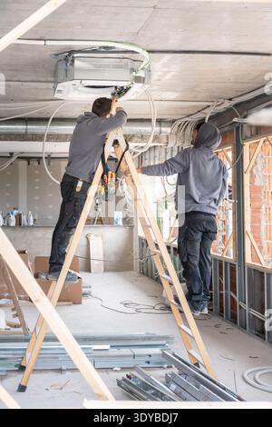 Air conditioning technicians installing hvac system during construction work Stock Photo