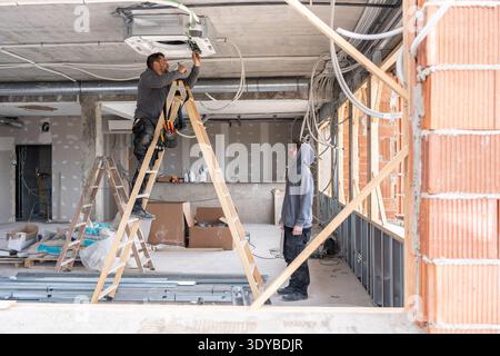 Hvac technicians installing air conditioning unit on a construction site Stock Photo