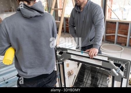 Hvac technicians installing air conditioning unit at construction site Stock Photo