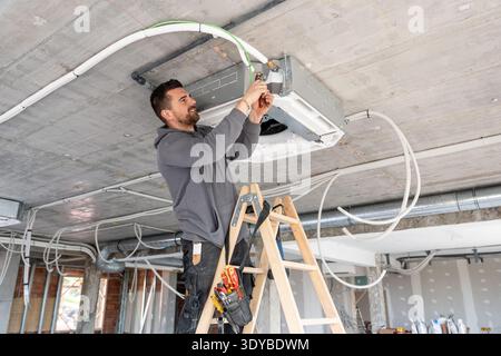 Hvac technician installing air conditioning unit on construction site Stock Photo