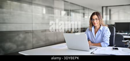 Busy middle aged business woman using laptop computer working in office. Stock Photo