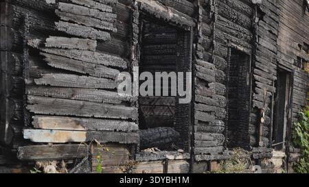 Burnt house structure showing extensive charring and fire damage Stock Photo