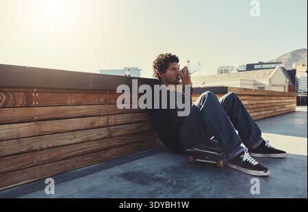 Skateboard, relax and man drinking water at skatepark for skating break, hydration and mockup space. Skater, african person and resting with liquid Stock Photo