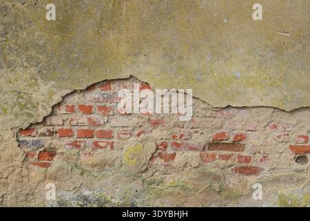 red bricks becoming visible in a broken wall Stock Photo