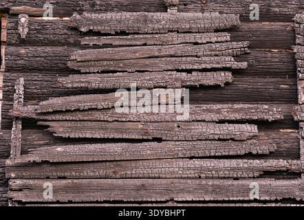Charred wood planks forming a rustic wall, showing fire damage and textured surface Stock Photo