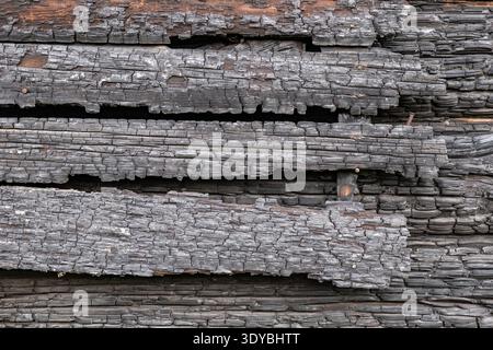 Charred wood planks showing fire damage and black ash texture background Stock Photo