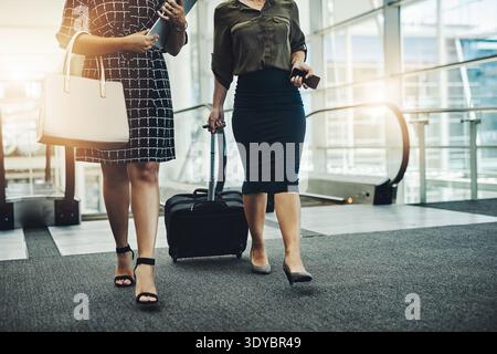 Business women, escalator and travel with suitcase in airport for convention, seminar or partnership. Female people, legs and luggage for flight Stock Photo