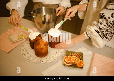 two women preparing homemade easter cakes with white glaze Stock Photo