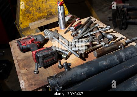 Mechanic worktable with wrenches, ratchet, sockets and battery drill beside spray can, depicting tool chaos before a service job begins in workshop Stock Photo