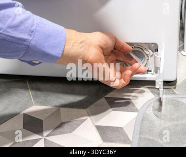 Man opening pump filter of the washing machine Stock Photo
