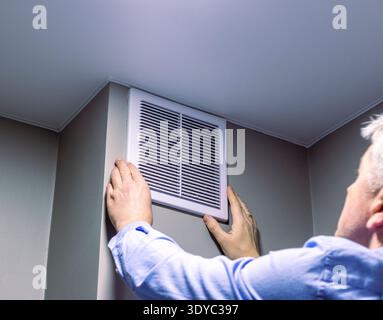 A person installing or maintaining an HVAC return air vent grille Stock Photo