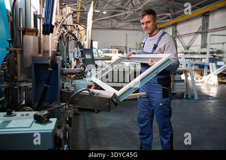 Professional production workers in coverall working with different PVC windows Stock Photo