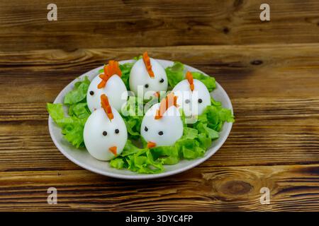 Funny easter breakfast with boiled eggs as chicks on wooden table Stock Photo