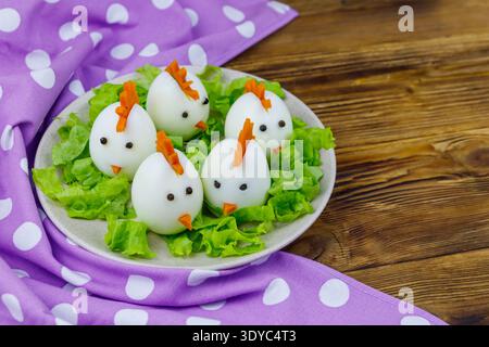 Funny easter breakfast with boiled eggs as chicks on wooden table Stock Photo
