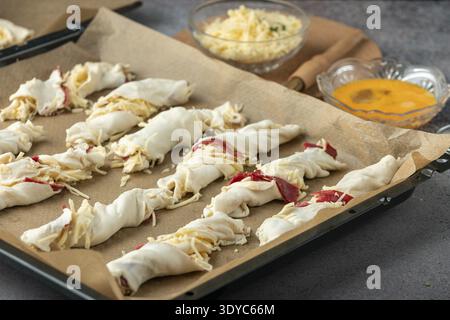 Dough rolls with ham and cheese on a baking tray to prepare for baking Stock Photo