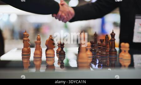Handshake over chess board symbolizing business strategy, agreement, and partnership Stock Photo