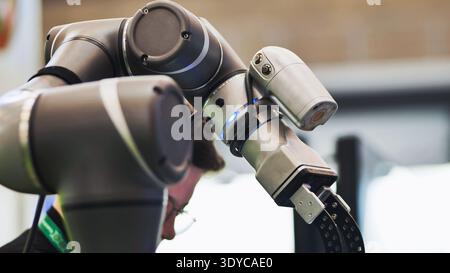 Minsk, Belarus - May 15, 2024: Robotic arm performing tasks in a modern factory with engineer supervising Stock Photo