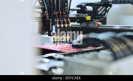 Automated machinery mounting electronic components on a red PCB Stock Photo