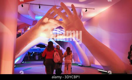Moscow, Russia - August 17, 2025: Guests exploring modern art exhibition featuring large human hands forming a heart shape Stock Photo