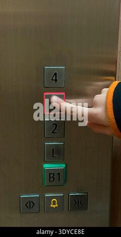 The child is pressing the button in the elevator Stock Photo