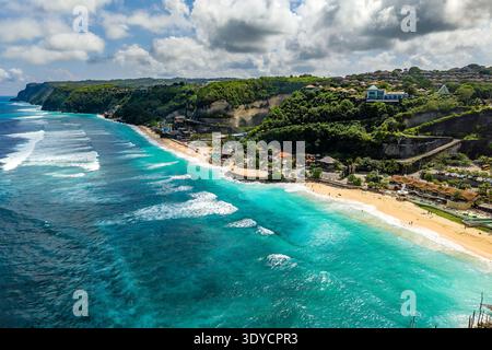 Turquoise ocean waves rolling onto sandy Melasti Beach below lush green cliffs in Bali Stock Photo