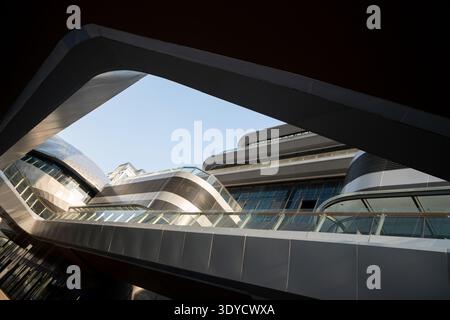 A low-angle view of the bold, curved metal and glass structure of a modern office building, showcasing contemporary architectural design. Stock Photo