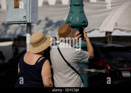 Senior couple taking photo with smartphone, smartphone technology in modern tourism lifestyle, rear view, outdoors in city. Stock Photo