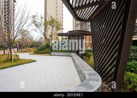 Detailed view looking out from underneath a contemporary dark slatted shade structure across a curved paved walkway and green lawn. The image conveys Stock Photo