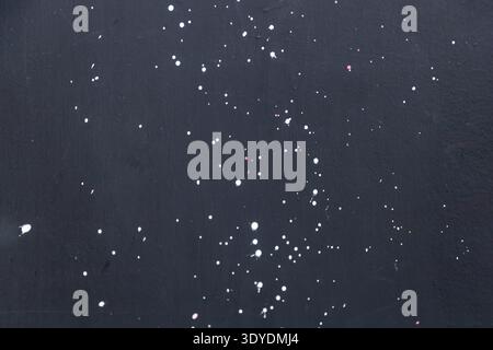 Abstract background of white paint splatters on a dark matte surface. Stock Photo