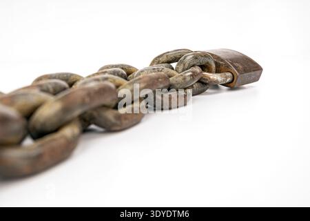 A heavy, rusted metal chain with an old padlock laid on a pristine white background. The image highlights the chain’s robustness and industrial aged t Stock Photo