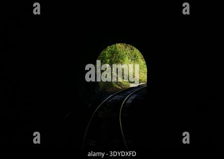 View from a train as it approaches the light at the end of a dark tunnel Stock Photo