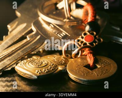 Golden keys hang beside ancient coins. Red beads and charms add cultural detail. Warm light highlights texture and history. Perfect for themes of trad Stock Photo