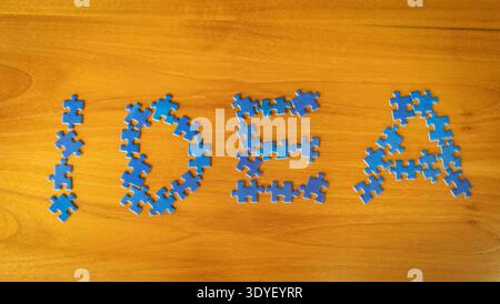 Idea concept written with blue puzzle pieces arranged on a wooden table. Creative representation of innovation, brainstorming, problem solving Stock Photo