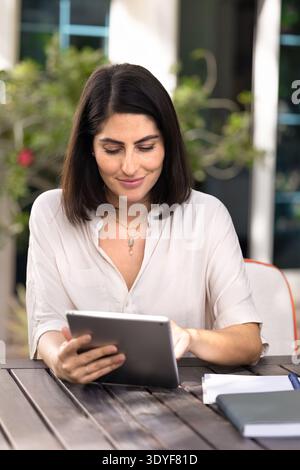 Positive young Latin woman using business application on digital tablet Stock Photo