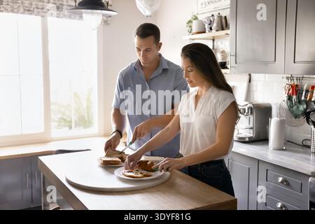 Caucasian married couple preparing breakfast together in kitchen Stock Photo