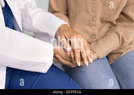 Close up of female doctor holding hands of woman patient Stock Photo