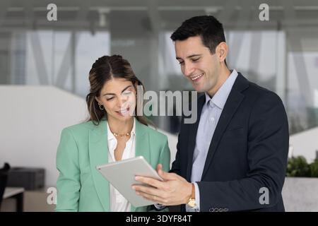 Diverse Hispanic colleagues engaged in teamwork using tablet in office Stock Photo