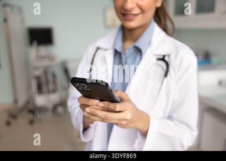 Close-up cropped image of female doctor using smartphone at workplace Stock Photo