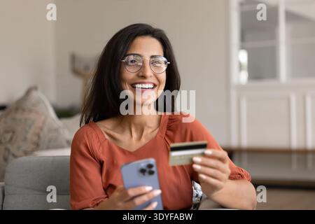 Happy woman using phone and bank card Stock Photo