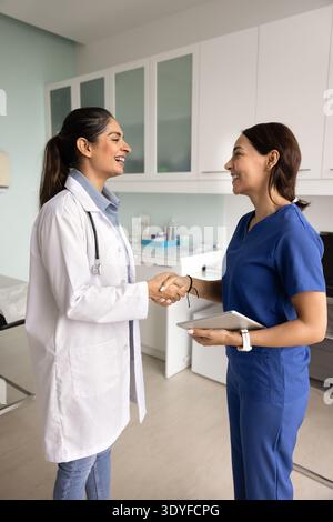 Smiling female doctors shaking hands in modern clinic Stock Photo