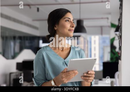 Confident Latina businesswoman planning strategy using digital tablet in office Stock Photo