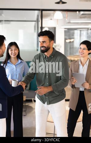 Cheerful businessmen, colleagues shaking hands, starting group meeting Stock Photo