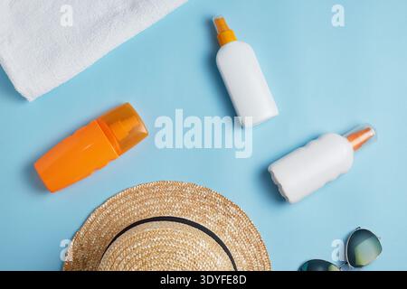 Sun cream, sun hat, cream, sunscreen bottle, sun cream, lotion bottle, sunglasses seashells on a blue background. Sun protection. Beach flat lay acces Stock Photo