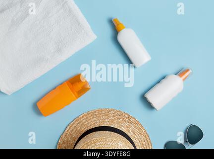 beach bag with beach accessories on a colored background top view. Sunscreen, towel, glasses, hat. Stock Photo