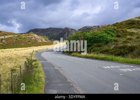 Two lane road with footpath winds through rugged North Wales countryside Stock Photo